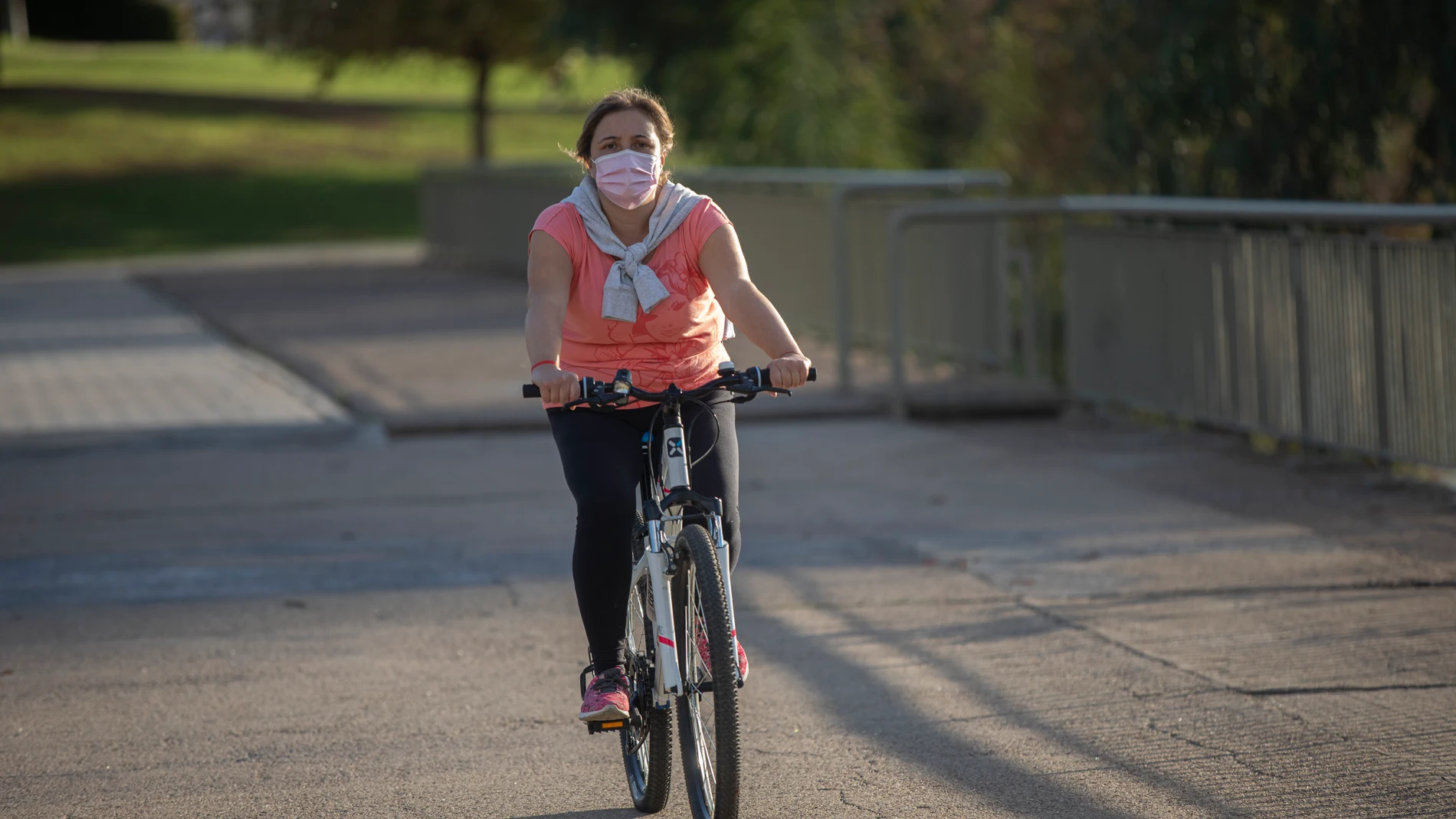 Una mujer con mascarilla pasea en bicicleta