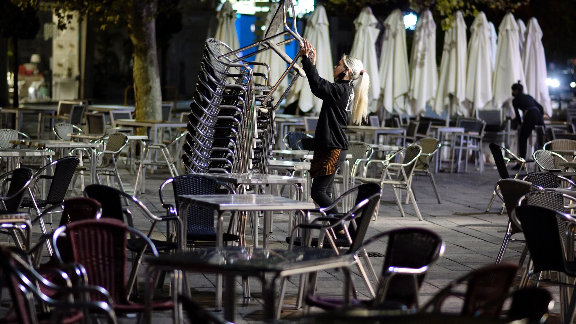 Una camarera recoge la terraza de un bar en Valladolid momentos antes del inicio del toque de queda impuesto por la Junta de Castilla y León debido al alto número de contagios de coronavirus en la Comunidad. EFE/NACHO GALLEGO