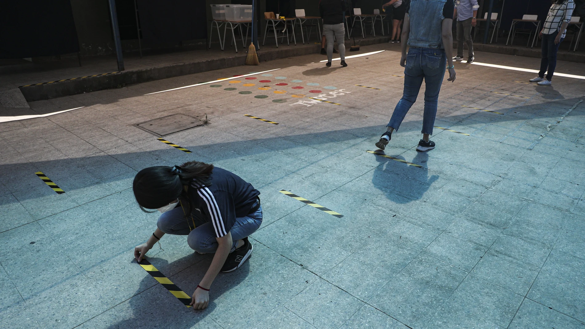 Empleados en Santiago de Chile colocan cintas en un centro de votación en el suelo para el referéndum