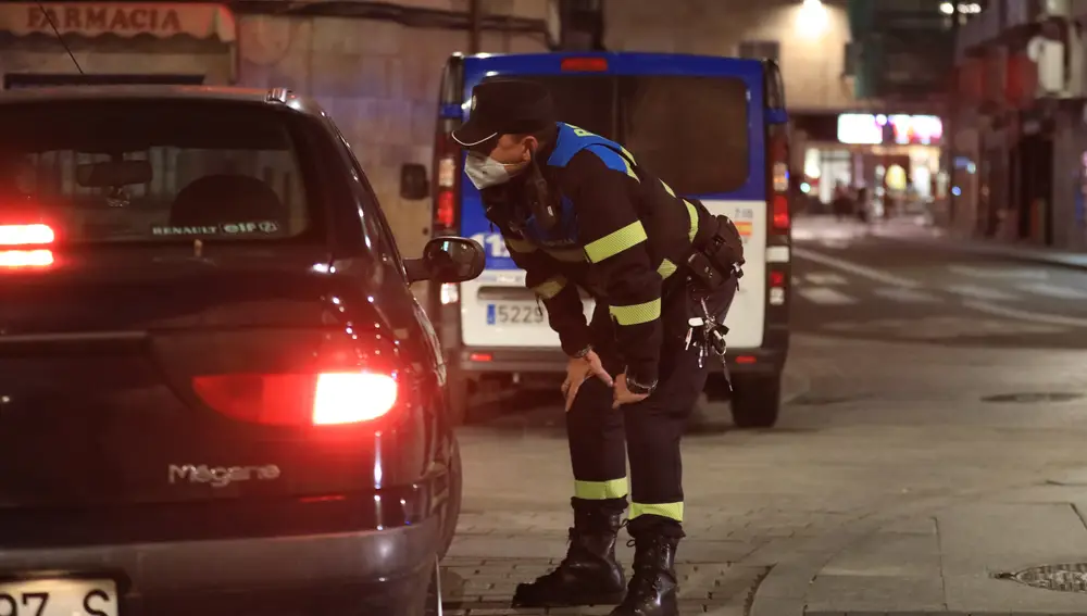 Un policía local se acerca a hablar con ciudadanos que están en un coche en Salamanca