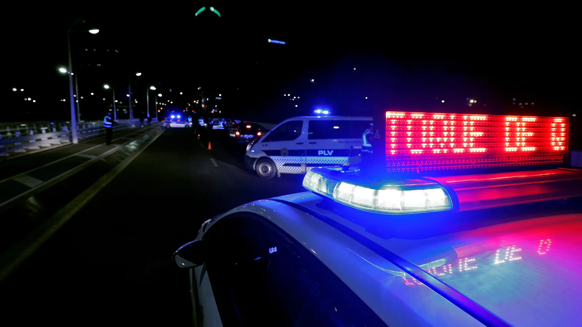 Agentes de la Policía Local de Valencia detienen en un control montado en el puente Assut de l'Or, a los vehículos que aún circulan tras la entrada en vigor del toque de queda.