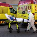 Un sanitaris con equipo de protección especial para evitar contagios de coronavirus traslada a un paciente de una ambulancia a urgencias del Hospital Clínico de València.