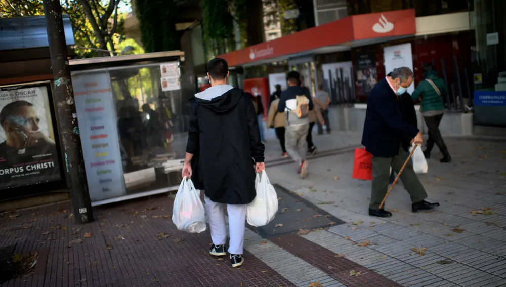 Un hombre lleva varias bolsas de supermercado en la zona básica de salud de Guzmán el Bueno, en el distrito de Chamberí.