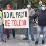Un grupo de personas sostiene una pancarta donde se puede leer "No al pacto de Toledo" en las inmediaciones del Congreso de los Diputado