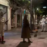 Un par de operarios municipales realizan labores de desinfección, en la calle del Paseo de Ourense, en la madrugada de este martes