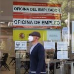 Un hombre con mascarilla pasa por una oficina de empleo de Madrid