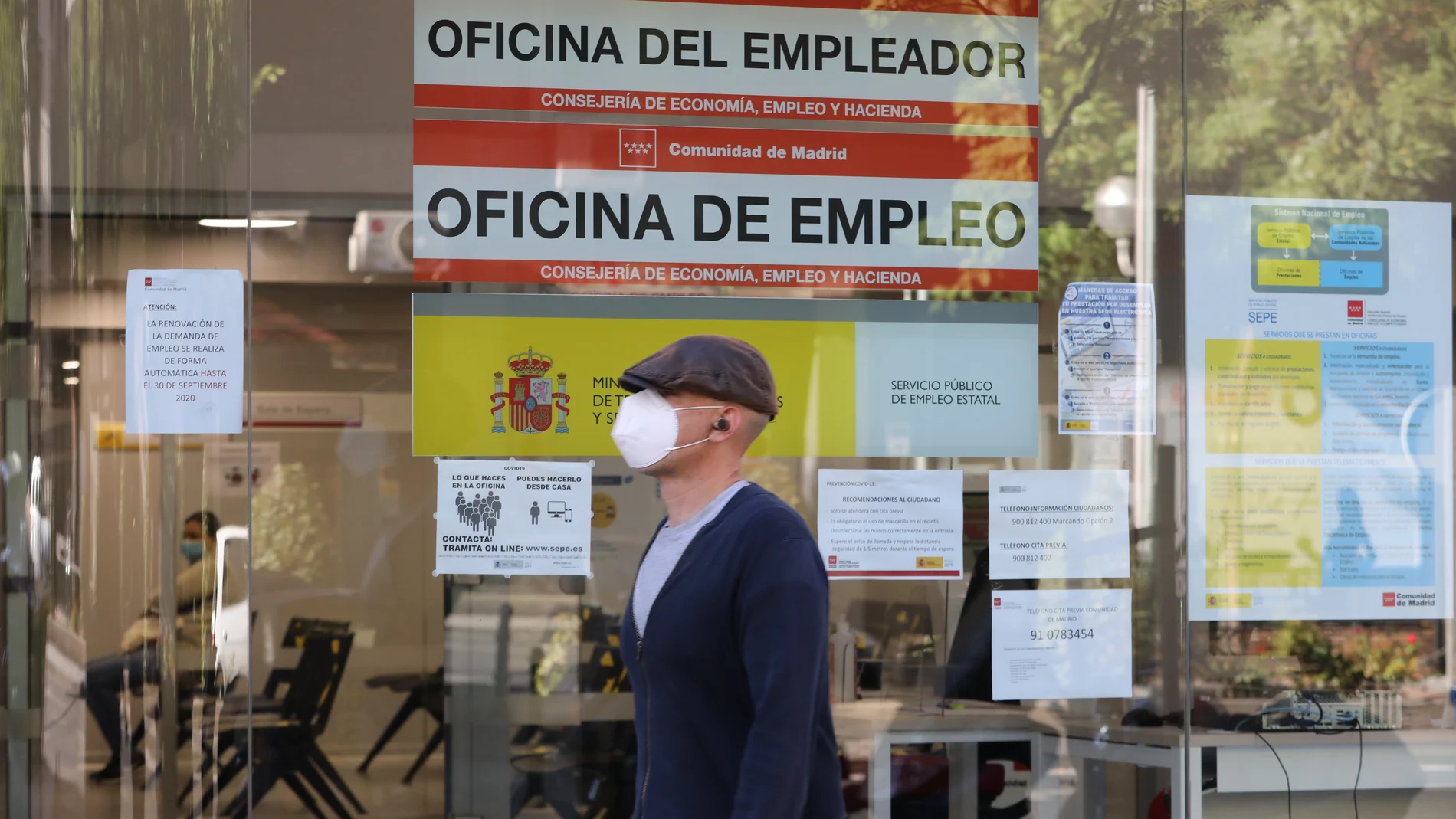 Un hombre con mascarilla pasa por una oficina de empleo de Madrid