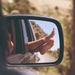 En la imagen, una mujer saca los pies por la ventanilla del coche.