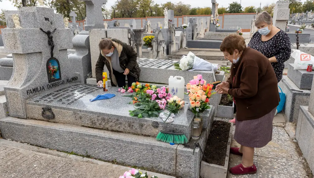 Unas mujeres limpian las lápidas y llevan flores