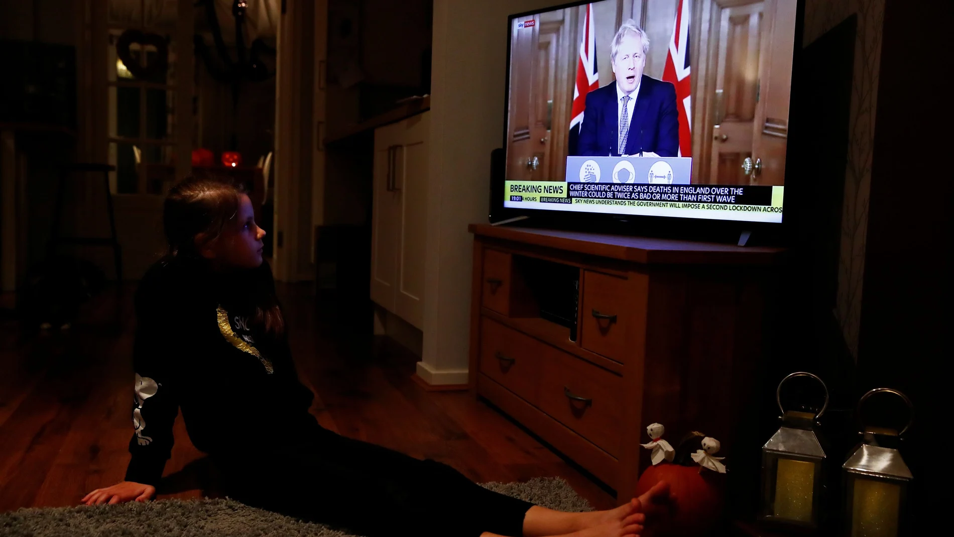 Una niña mira a Boris Johnson en la tele mientras se anuncia otro confinamiento