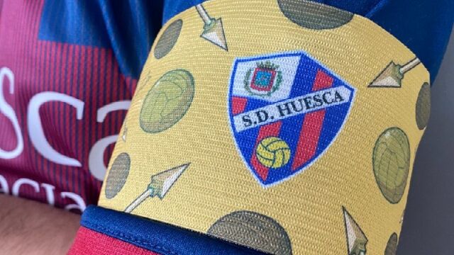 Saetas, balones de cuero y de oro en homenaje a Di Stéfano en el brazalete de capitán del Huesca