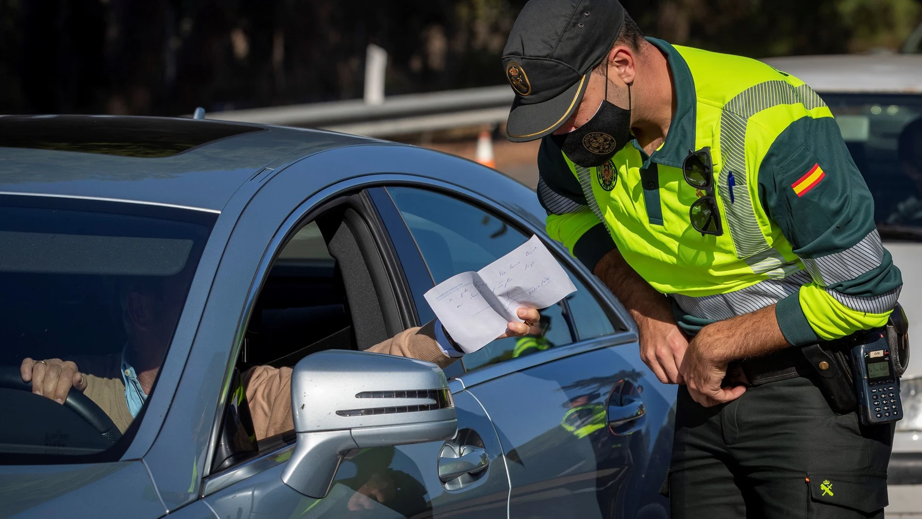 Un agente de la Guardia Civil de Tráfico comprueba un documento aportado por un conductor durante un control establecido en la autopista AP-4 Sevilla-Cádiz