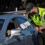 Un agente de la Guardia Civil de Tráfico comprueba un documento aportado por un conductor durante un control establecido en la autopista AP-4 Sevilla-Cádiz