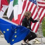 Una mujer trata de sujetar las banderas de EE UU y la UE en una reunión del G-7 en 2018