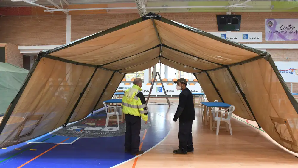 SAN ANDRÉS DEL RABANEDO (LEÓN), 06/11/20.- Dos operarios conversan junto a una de las carpas montadas en el pabellón deportivo Camino de Santiago de la localidad leonesa de San Andrés de Rabanedo, este viernes, donde mañana se realizarán test masivos de antígenos de segunda generación a la población de la localidad. EFE/J.Casares