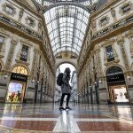A woman walks in downtown's Vittorio Emanuele gallery, with fashion shops closed in background, Friday, Nov. 6, 2020. Lombardy is among the four Italian regions classified as red zones, where a strict lockdown was imposed starting Friday - to be reassessed in two weeks - in an effort to curb the COVID-19 infections growing curve. Starting today, only shops selling food and other essentials are allowed to open. (Claudio Furlan/LaPresse via AP)