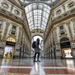 A woman walks in downtown&#39;s Vittorio Emanuele gallery, with fashion shops closed in background, Friday, Nov. 6, 2020. Lombardy is among the four Italian regions classified as red zones, where a strict lockdown was imposed starting Friday - to be reassessed in two weeks - in an effort to curb the COVID-19 infections growing curve. Starting today, only shops selling food and other essentials are allowed to open. (Claudio Furlan/LaPresse via AP)