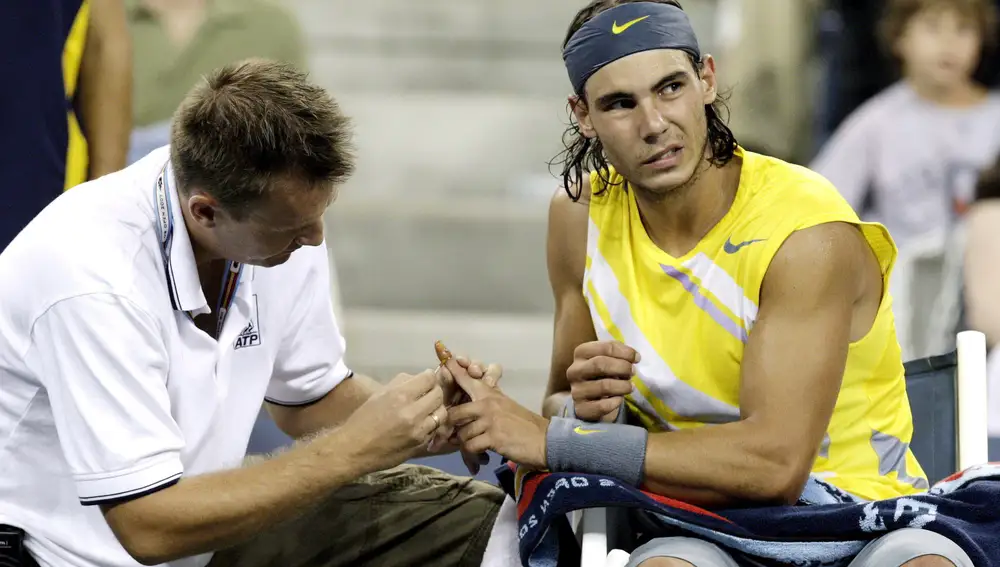 El español Rafael Nadal es atendido por su entrenador tras una lesión en uno de sus dedos.