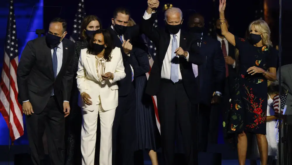 Joe Biden sostiene la mano de su hijo Hunter, mientras ellos y la candidata a la vicepresidencia Kamala Harris celebran con sus familias la victoria demócrata