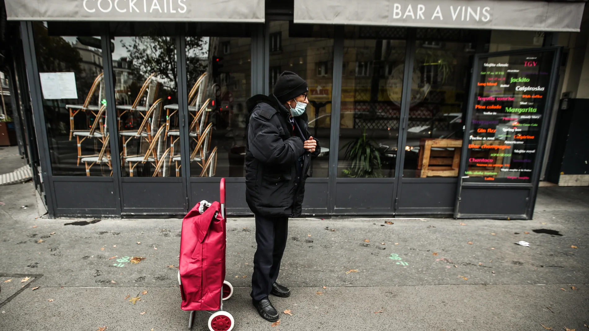 Un anciano con mascarilla, junto a un restaurante cerrado, en París
