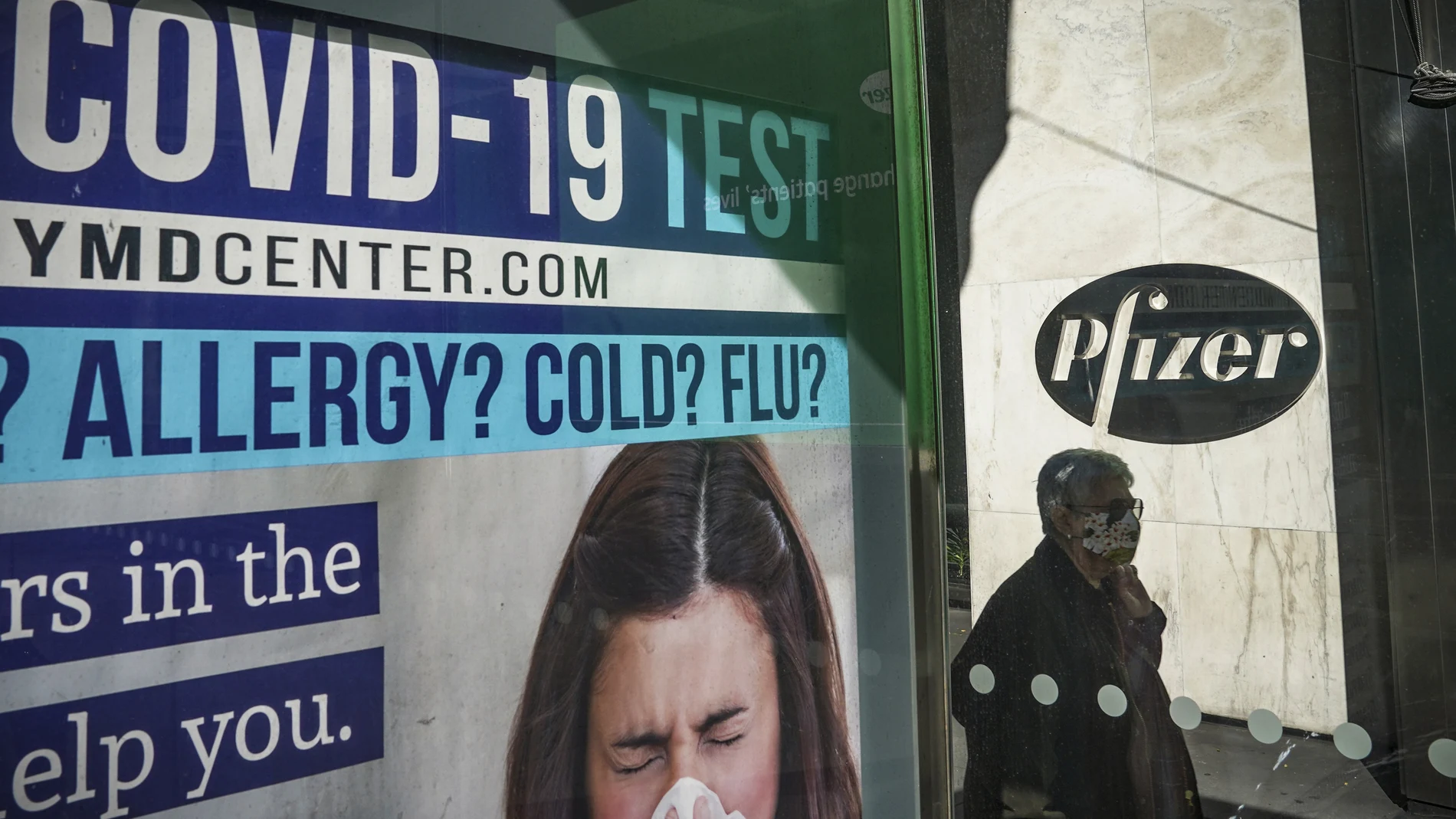 A bus stop ad for COVID-19 testing is shown outside Pfizer world headquarters in New York on Monday Nov. 9, 2020. Pfizer says an early peek at its vaccine data suggests the shots may be 90% effective at preventing COVID-19, but it doesn't mean a vaccine is imminent. (AP Photo/Bebeto Matthews)