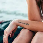 En la imagen, una chica presume de sus tatuajes frente al mar.