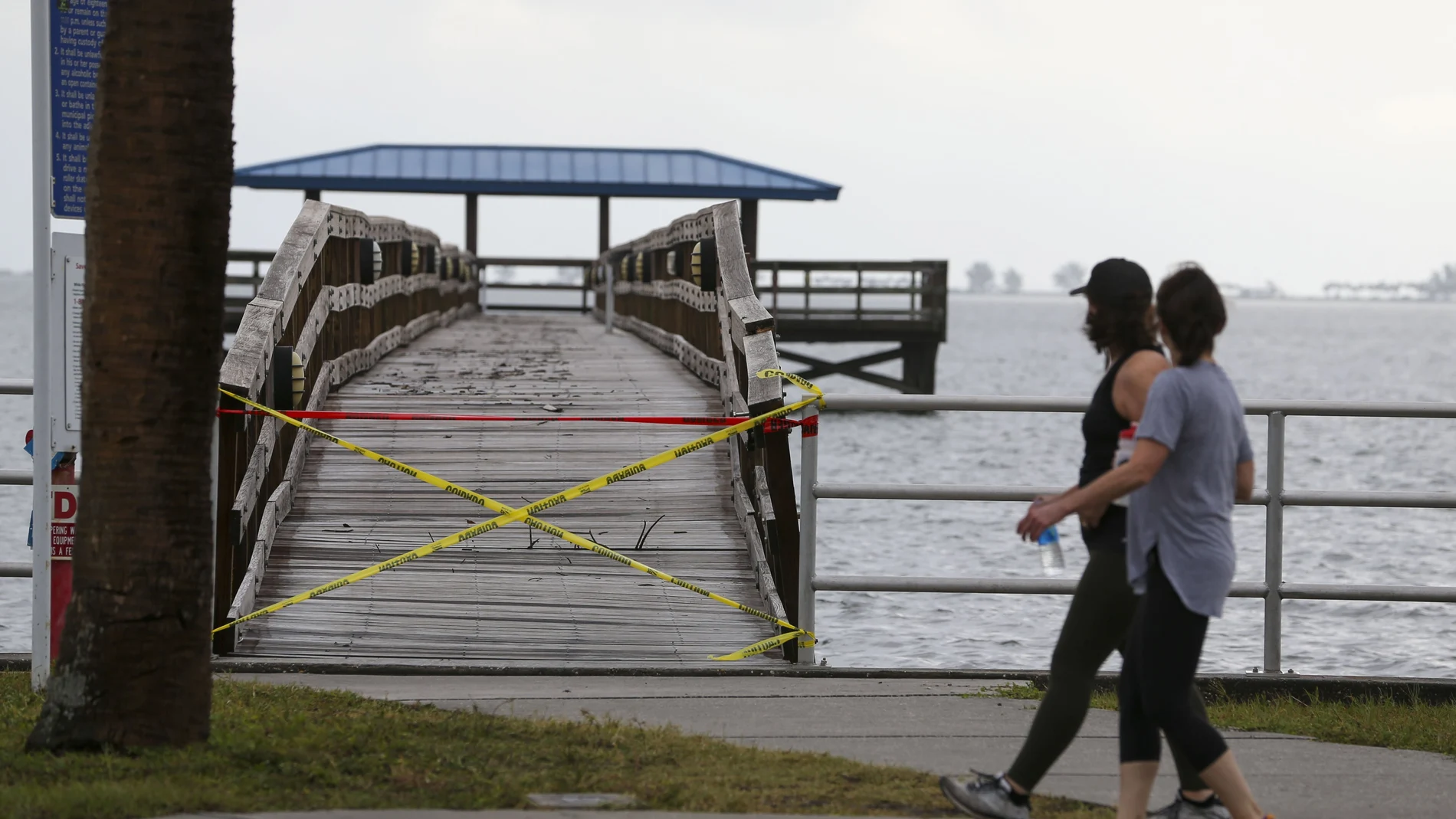 Pedestrians walk past a damaged pier Thursday, Nov. 12, 2020, in Safety Harbor, Fla. Tropical Storm Eta passed just off the coast of Pinellas County with torrential rain and storm surge. Eta dumped torrents of blustery rain on Florida's west coast as it moved over Florida after making landfall north of the heavily populated Tampa Bay area Thursday morning. (Chris Urso/Tampa Bay Times via AP)