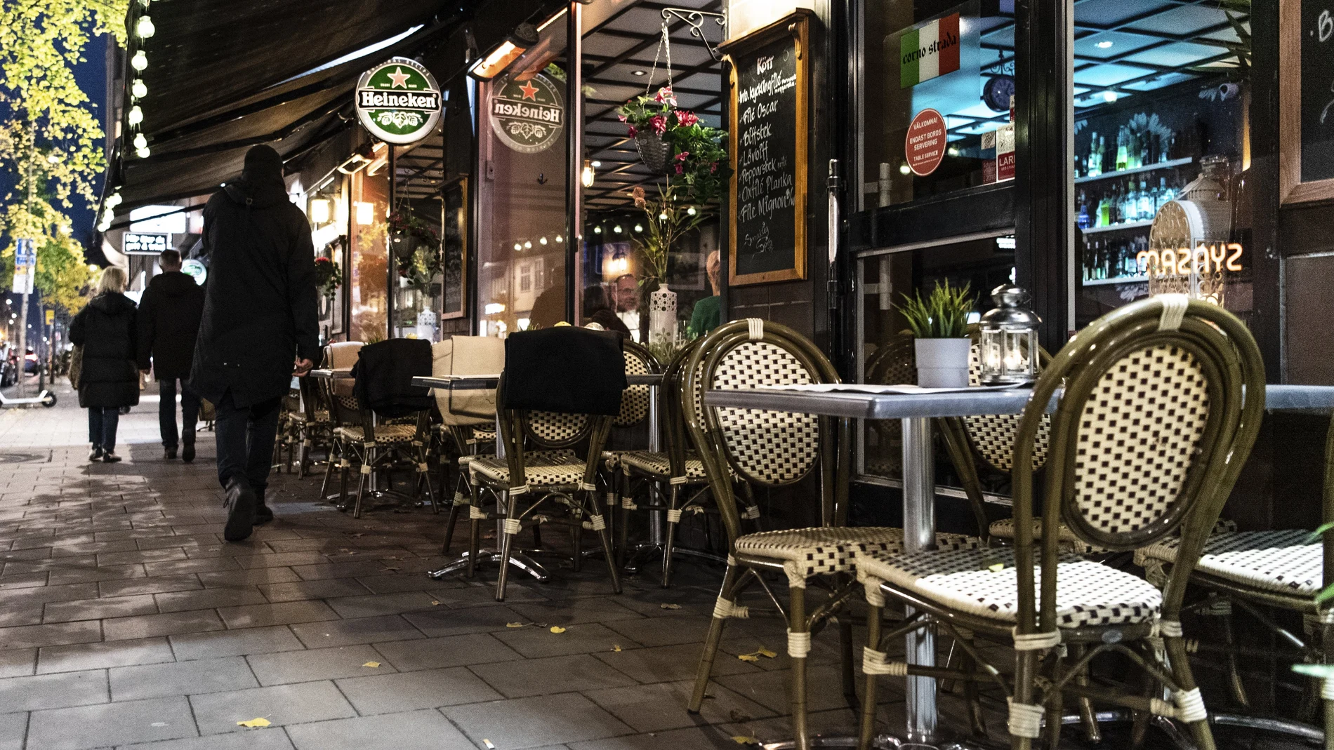 Viandantes pasan junto a un restaurante vacío en el centro de Estocolmo