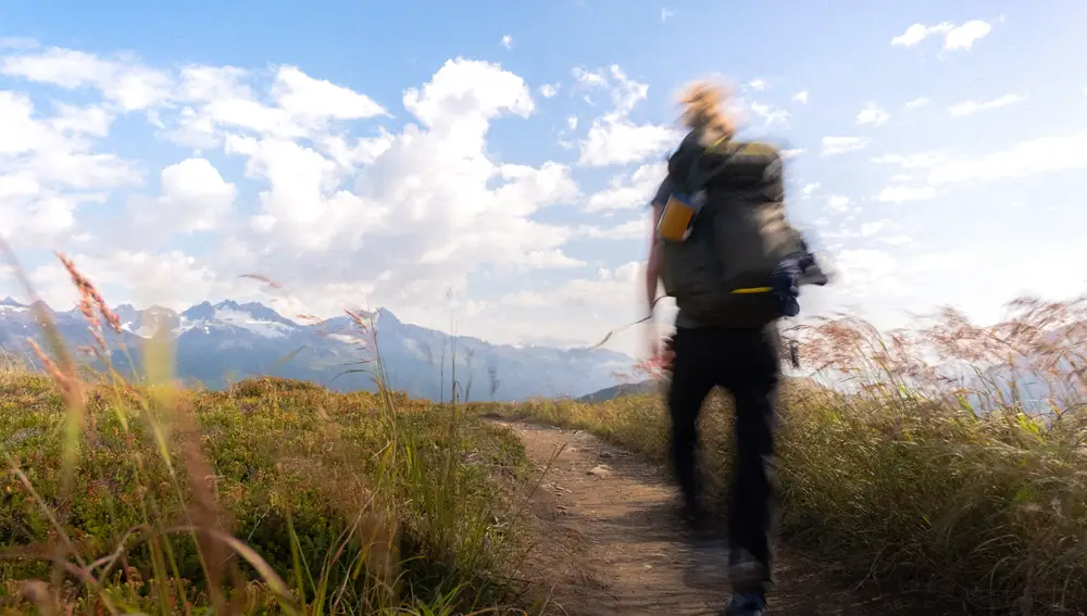 En la imagen, un hombre haciendo senderismo por la montaña.