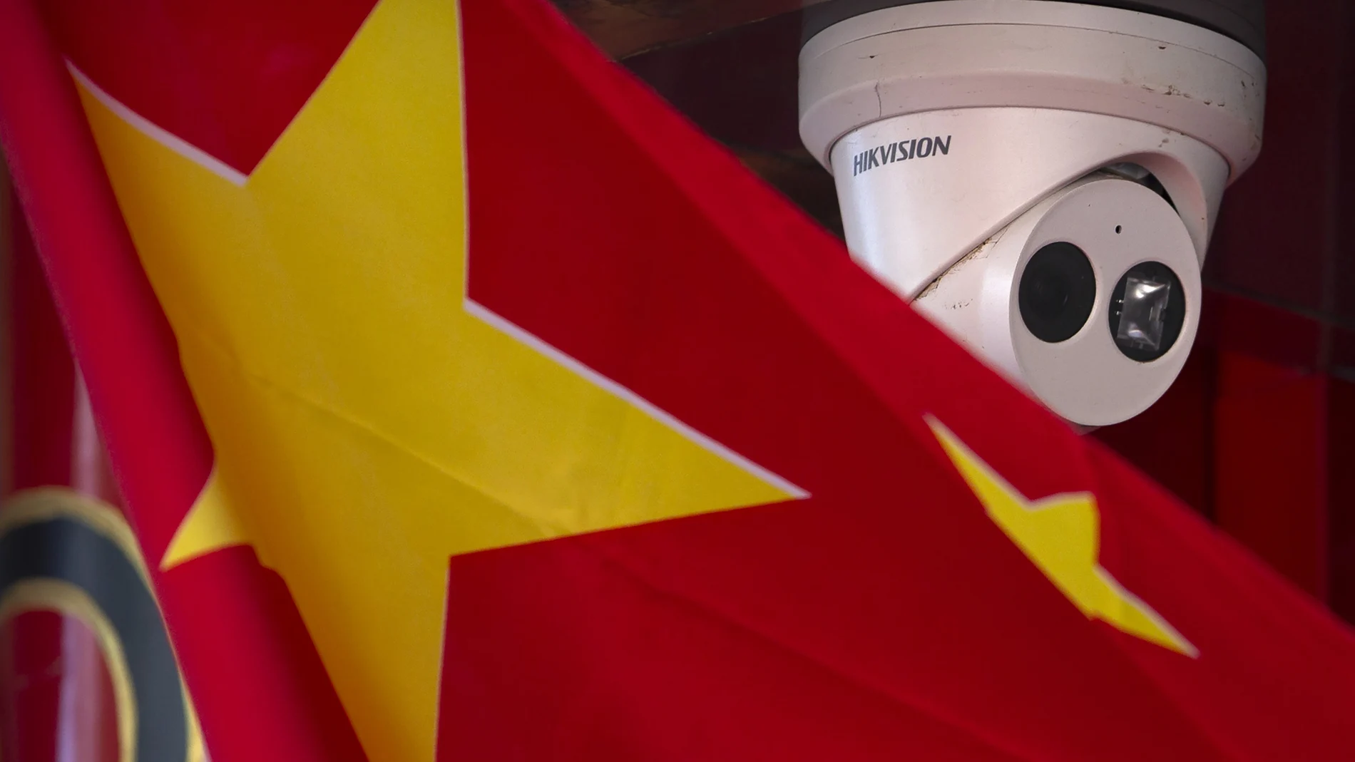 Una bandera china junto a una cámara de seguridad de la empresa Hikvision, afectada por la orden de Trump