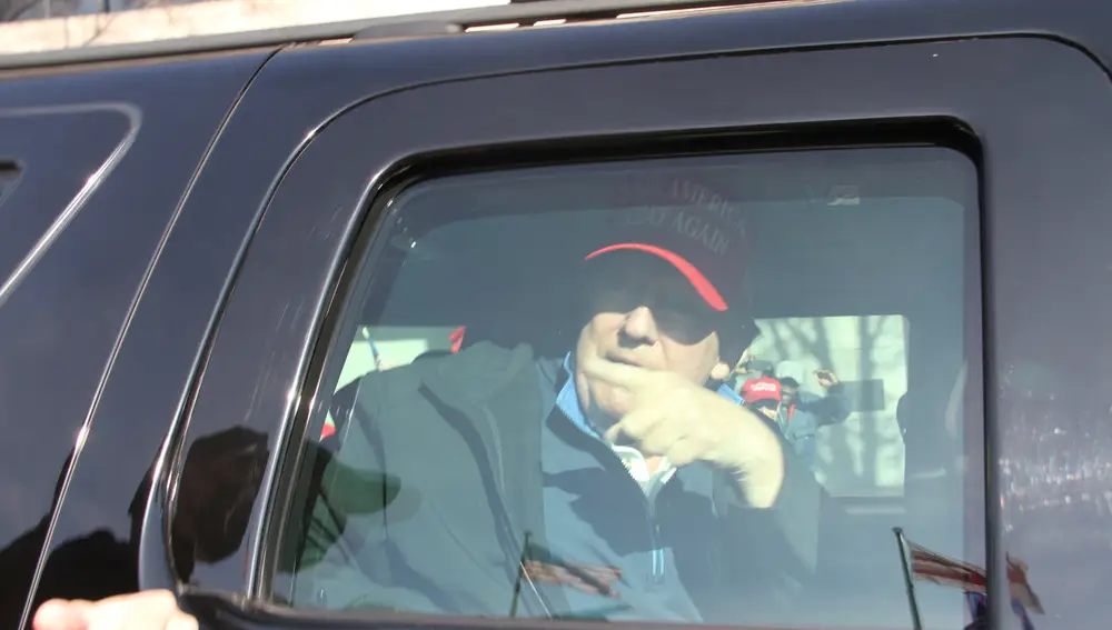 El presidente Donald Trump dentro de su coche, pasa por el lugar de la protesta de camino a jugar al golf