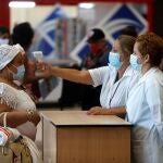 AME8519. LA HABANA (CUBA), 15/11/2020.- Trabajadoras del aeropuerto de La Habana toman la temperatura a una mujer en el primer día que reinicia las operaciones, suspendidas desde hace meses a causa de la pandemia, hoy en La Habana (CUBA). EFE/ Yander Zamora