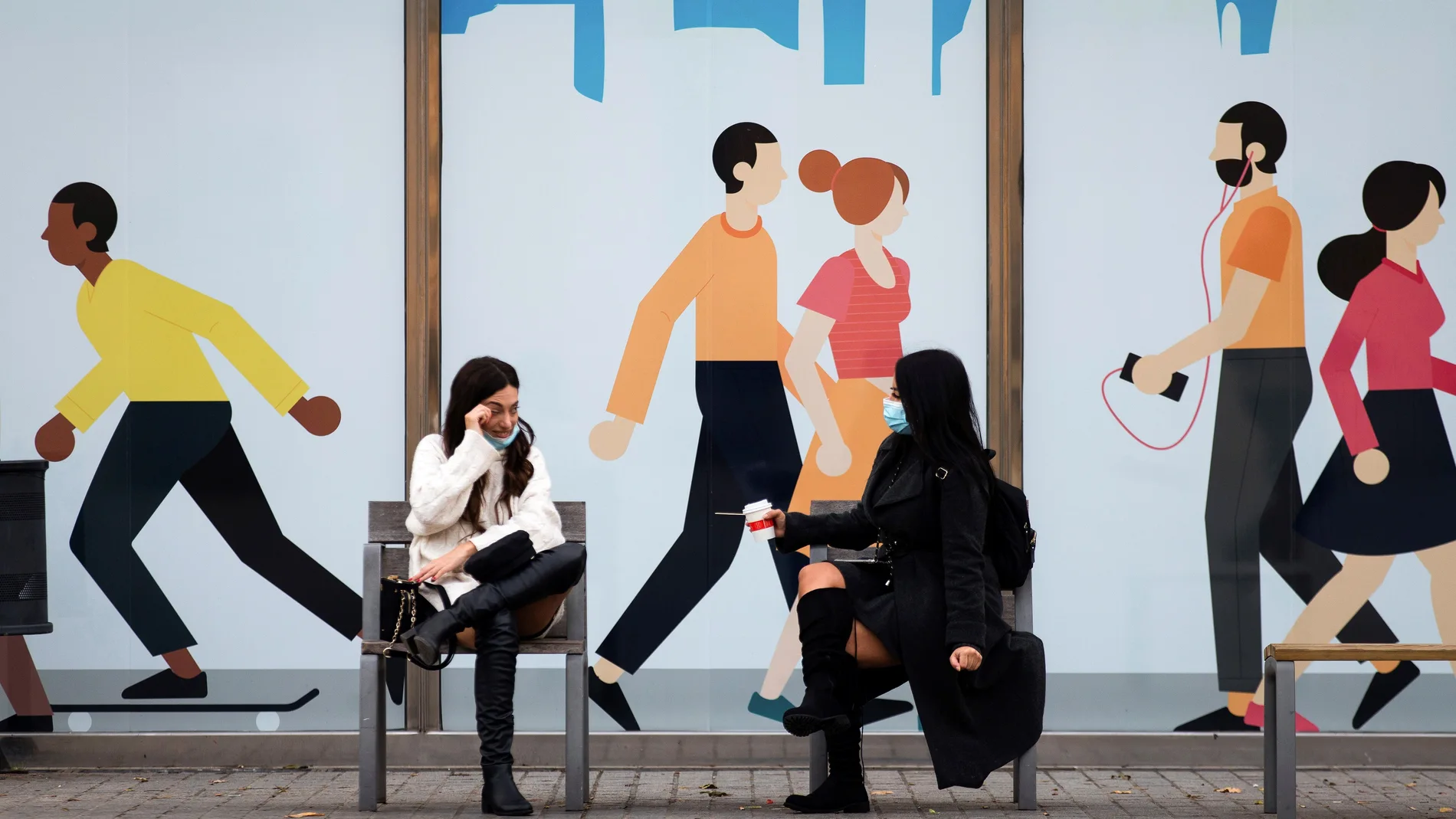 Dos mujeres conversan sentadas en un banco de las calles del barrio del Born de Barcelona