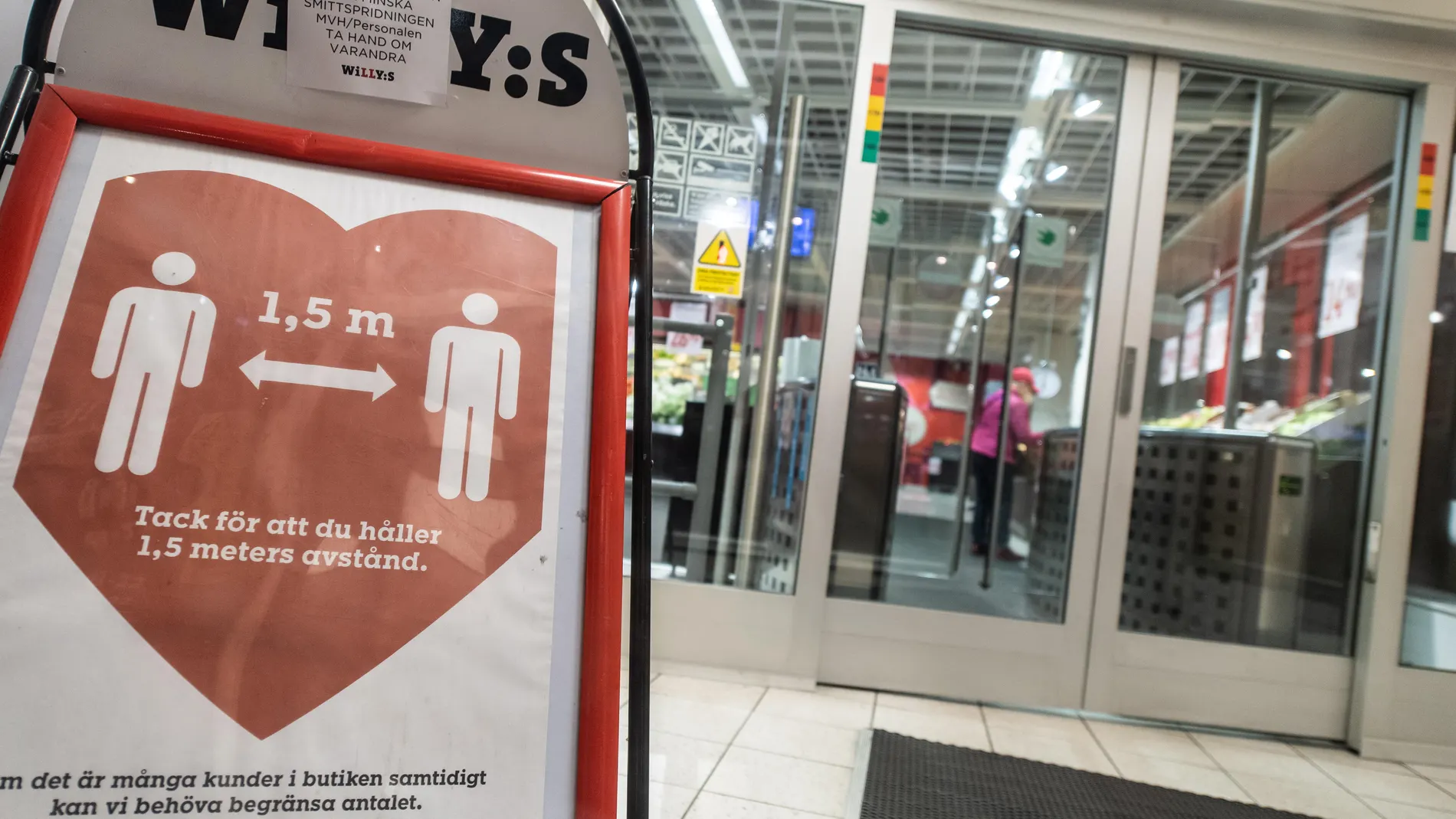 Un cartel recuerda a los ciudadanos mantener la distancia social a la entrada de un supermercado de Estocolmo