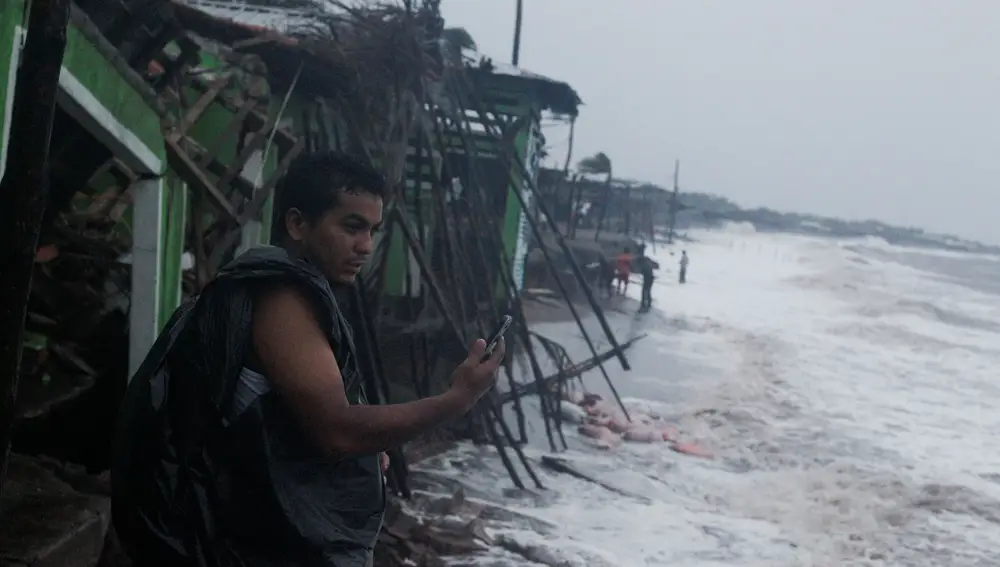 Un hombre observa si tiene cobertura en la playa de Cedeno, Honduras