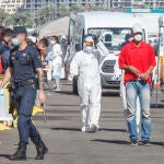 Un policía nacional junto a un grupo de inmigrantes ilegales en el puerto de ArguineguinEuropa Press18/11/2020