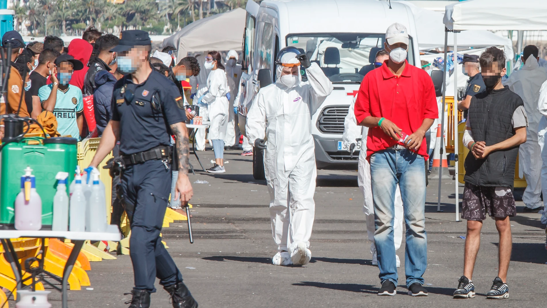 Un policía nacional junto a un grupo de inmigrantes ilegales en el puerto de ArguineguinEuropa Press18/11/2020