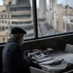 Un jubilado lee una revista en una cafetería de Gran Vía (Madrid)