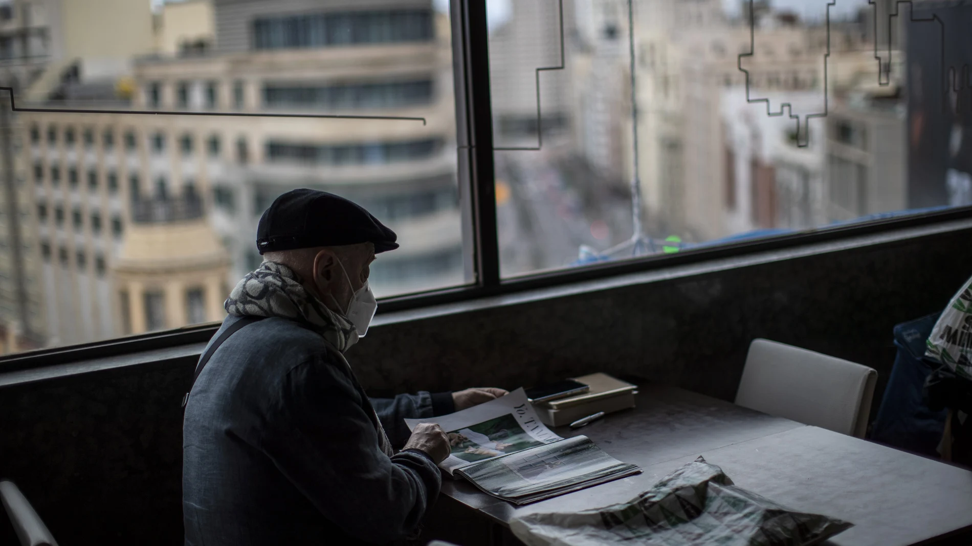 Un jubilado lee una revista en una cafetería de Gran Vía (Madrid)