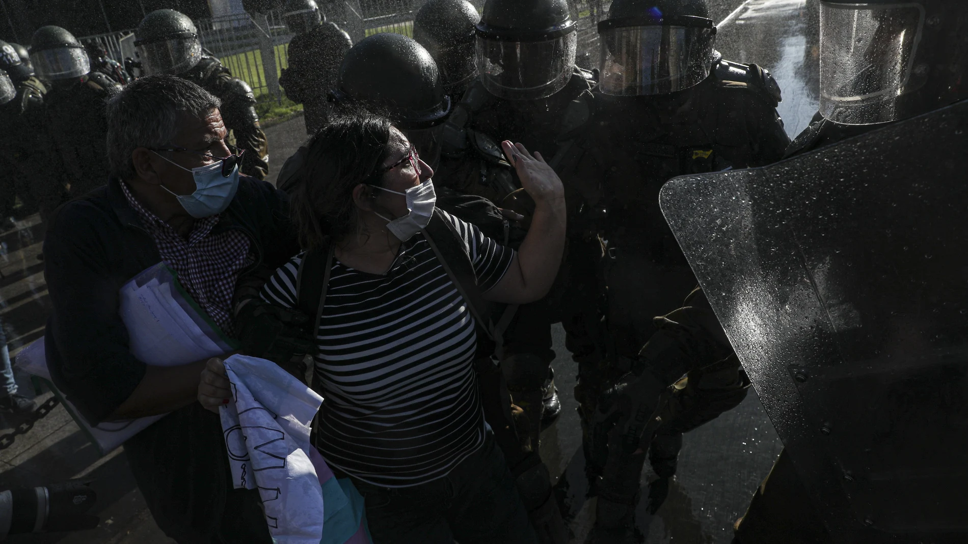 A couple of demonstrators scuffle with police outside of La Moneda presidential palace during a protest against President Sebastian Pi��era, demanding his resignation, in Santiago, Chile, Wednesday, Nov. 18, 2020. (AP Photo/Esteban Felix)