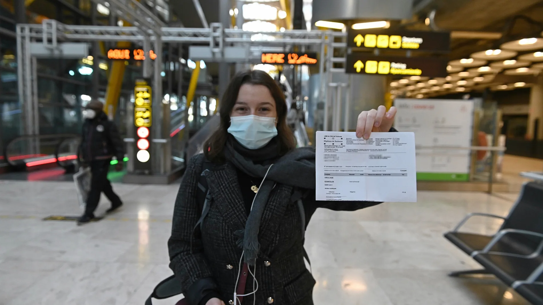 Una joven muestra el resultado de su PCR a su llegada al aeropuerto Adolfo Suárez-Barajas en Madrid, este lunes