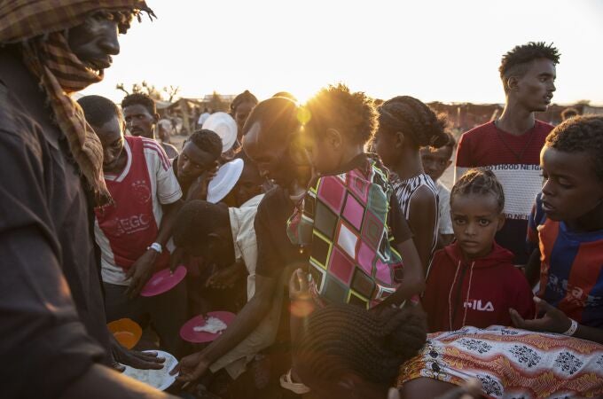Refugiados de Tigray que huyeron del conflicto en la región de Tigray de Etiopía, esperan a que voluntarios locales sudaneses les sirvan arroz cocido en el campamento de refugiados de Um Rakuba en Qadarif, en el este de Sudán