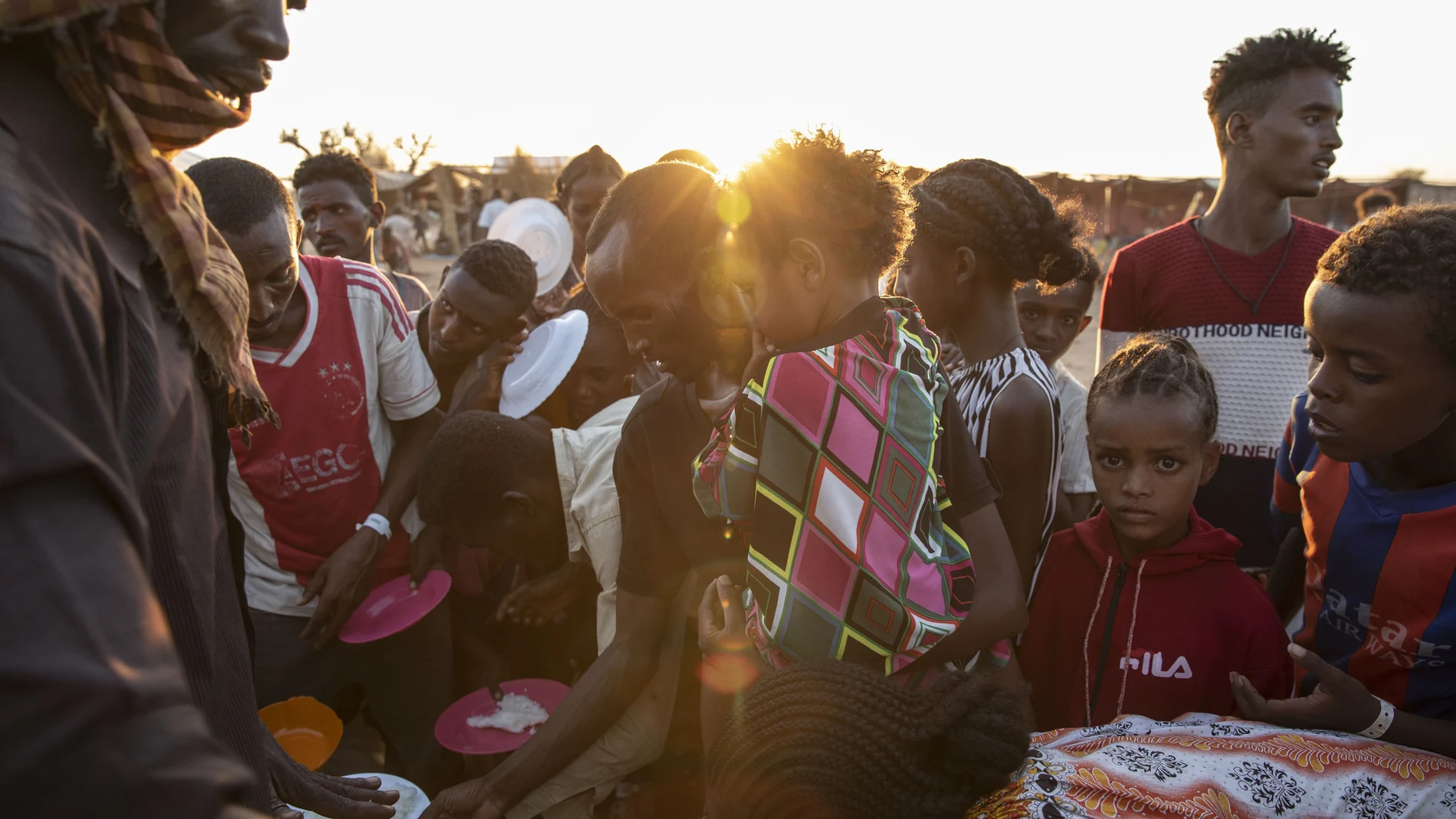 Refugiados de Tigray que huyeron del conflicto en la región de Tigray de Etiopía, esperan a que voluntarios locales sudaneses les sirvan arroz cocido en el campamento de refugiados de Um Rakuba en Qadarif, en el este de Sudán