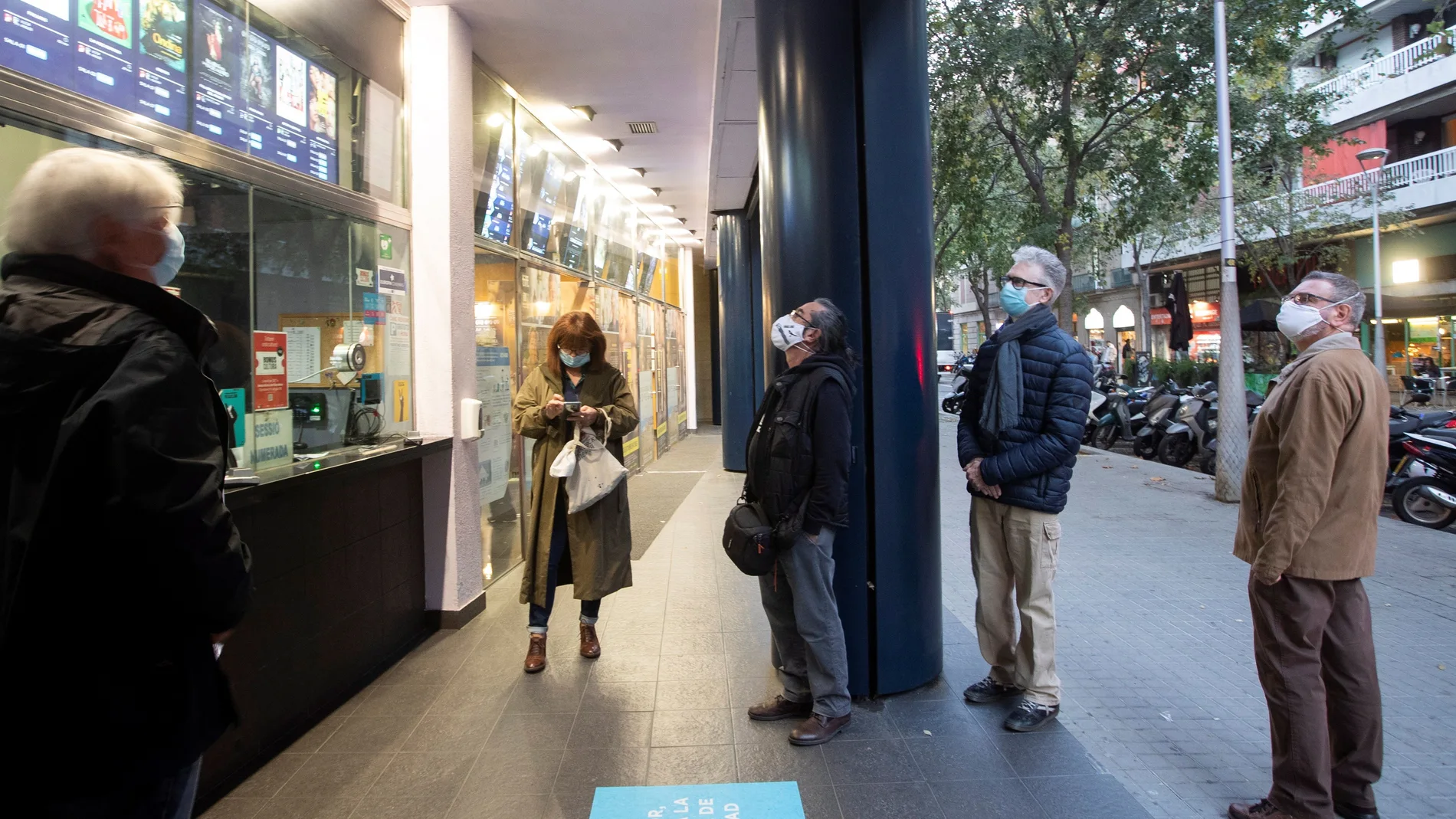 Varias personas comprueban la cartelera de los cines Renoir de Barcelona este lunes, cuando Cataluña, donde la situación epidemiológica por la pandemia de coronavirus sigue mejorando poco a poco, ha iniciado la desescalada con la reapertura de la restauración y de equipamientos culturales y deportivos, en todos los casos con aforo limitado, mientras se mantiene el toque de queda y el confinamiento perimetral municipal durante los fines de semana.