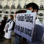 Un trabajador sanitario sostiene una pancarta durante una concentración por la mejora de la sanidad pública