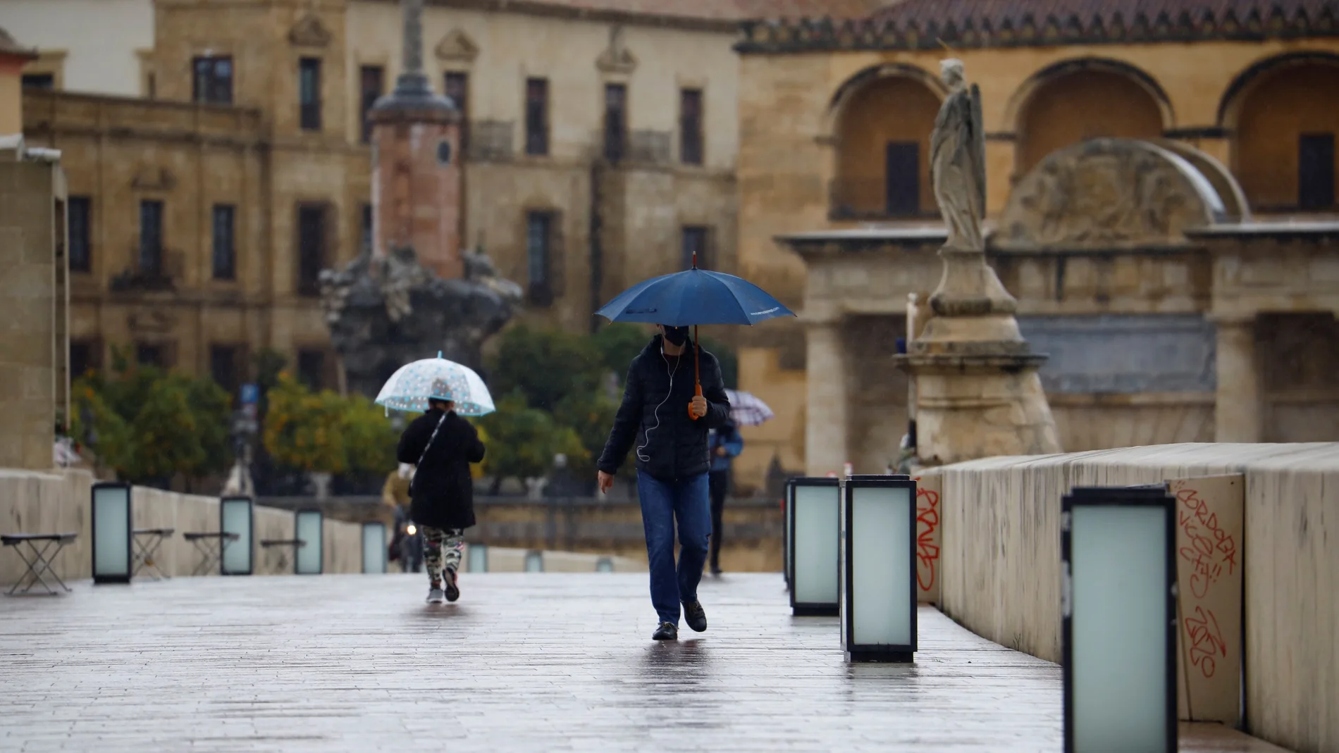 CÓRDOBA.-Unas personas se protegen con paraguas de la lluvia mientras caminan por el Puente Romano de Córdoba. EFE/Salas