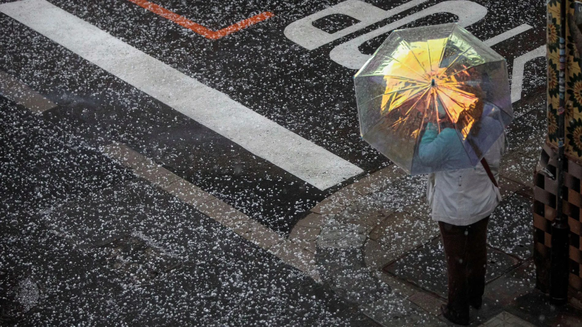 Una persona se protege del granizo con un paraguas este viernes en la ciudad de Valéncia. Las provincias de Castellón y Valencia están este viernes en alerta naranja por precipitaciones de intensidad muy fuerte y con tormenta, que podrían acumular 40 litros por metro cuadrado en una hora, mientras que la provincia de Alicante está en nivel amarillo por precipitaciones acumuladas en doce horas de 60 litros por metro cuadrado y de 30 litros por metro cuadrado en una hora