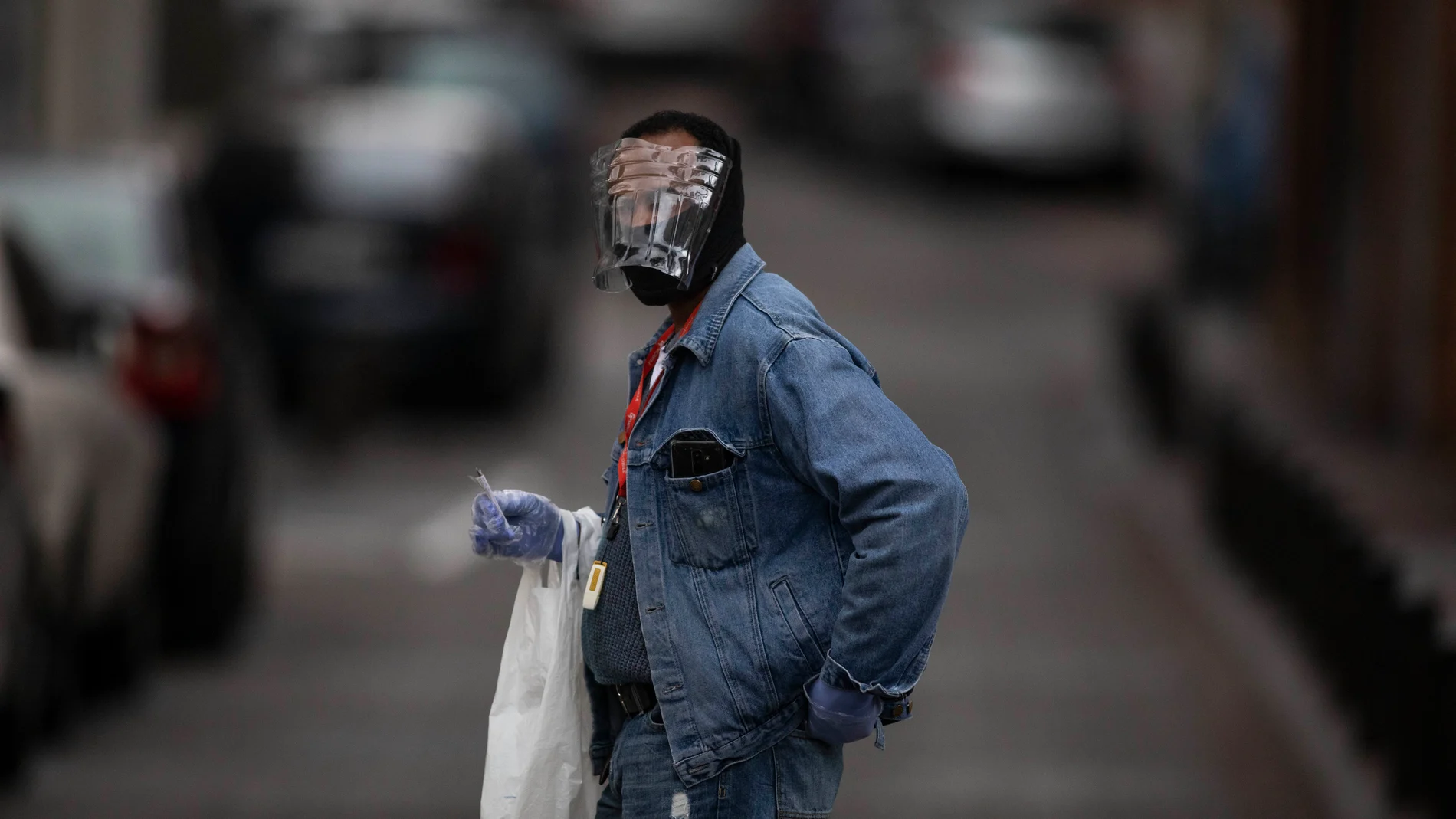 Una persona con un protector casero camina en Puente de Vallecas, Madrid, durante el estado de alerta del coronavirus.