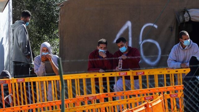 Varios de los inmigrantes alojados en el Centro de Atención Temprana a Extranjeros de Barranco Seco, en Las Palmas de Gran Canaria, junto a una de las vallas del recinto