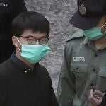 Joshua Wong escoltado por un funcionario de seguridad durante una vista de un juicio en 2020